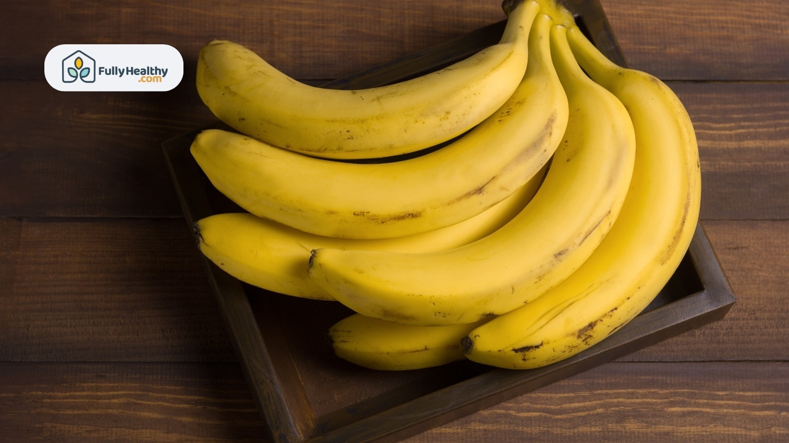 Fresh bananas in a wooden tray arranged in a neat pile