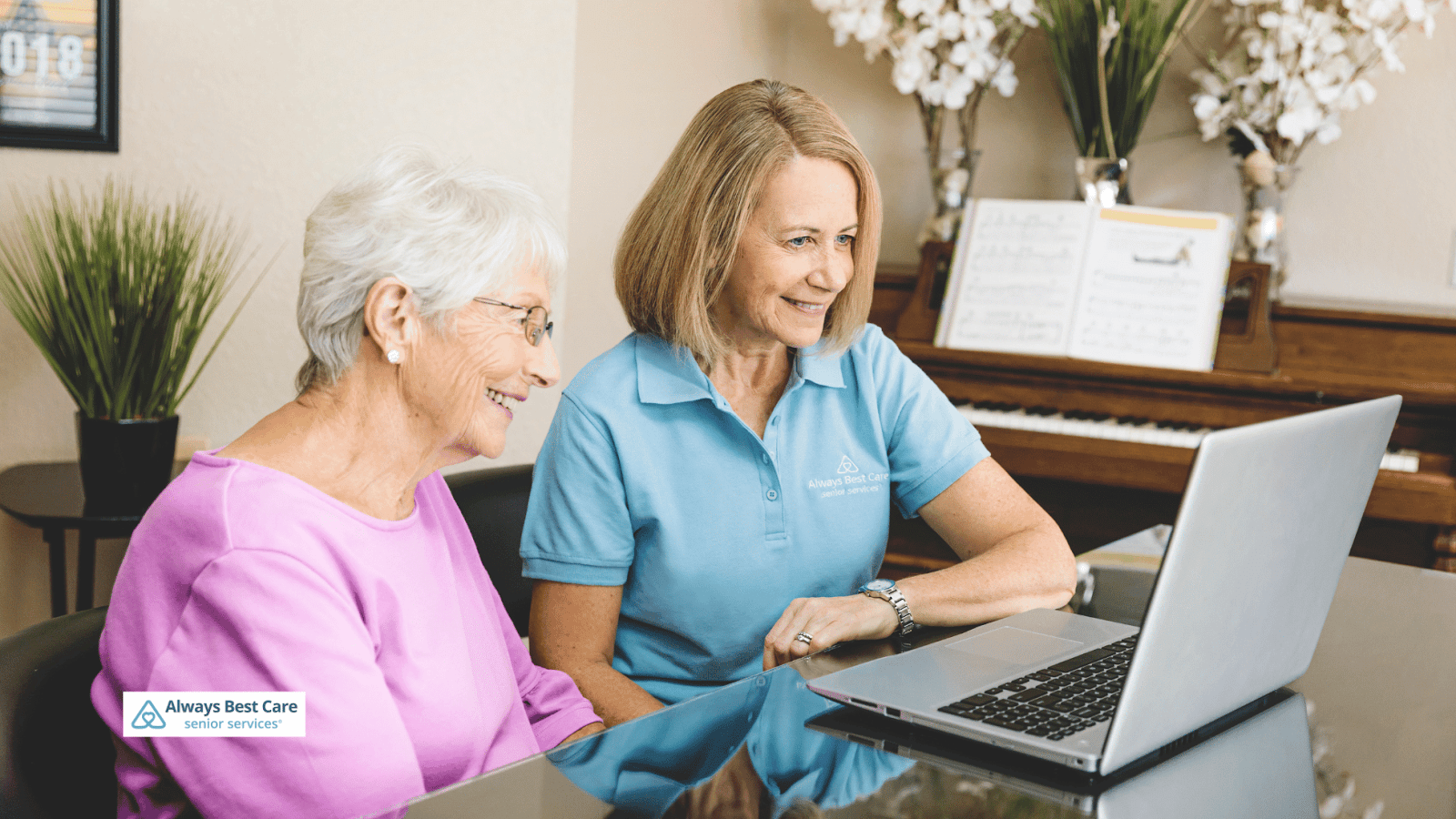 This is an image of a senior and a caregiver looking at a laptop screen together