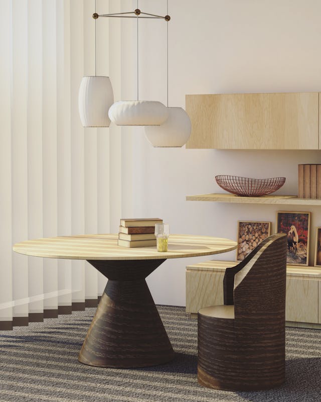 A modern dining area, reflecting Vastu Shastra principles, features a round wooden table with a conical base, paired with a curved wooden chair.