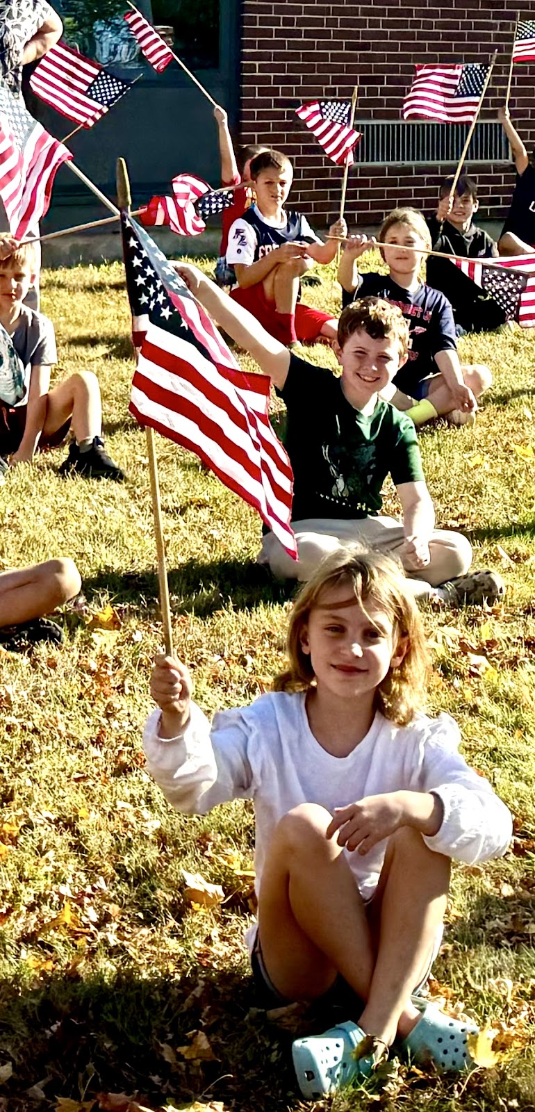 image of students holding flags on the front lawn of the school