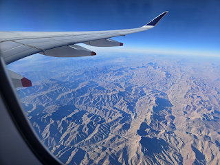 View out an airplane window showing very rugged, brown mountains below.