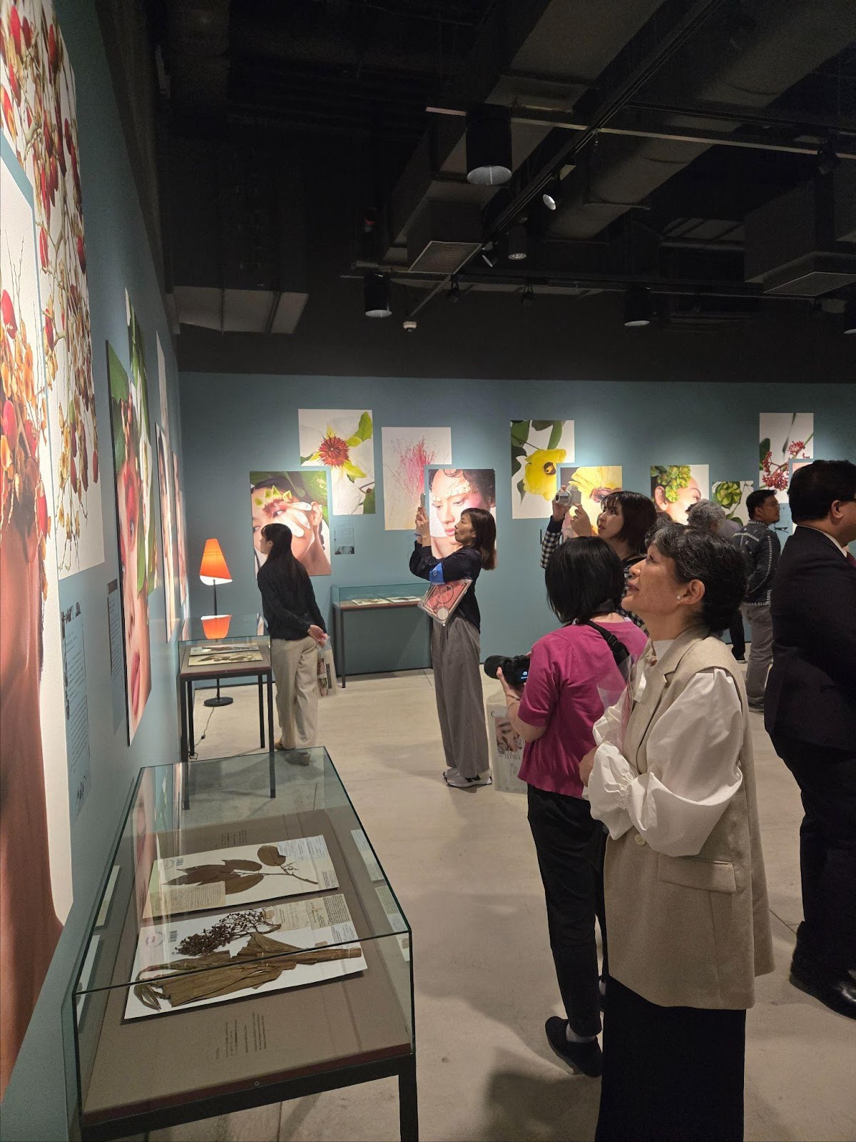 A group of people looking at pictures on the wallDescription automatically generated