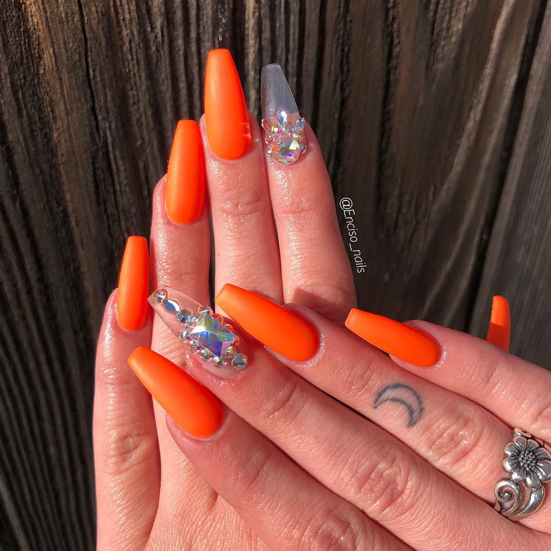 Close up of nails with glittery orange nails having Rhinestone Orange Nails