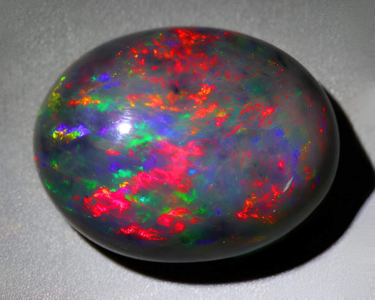 Natural gemstone fire black opal on gray background