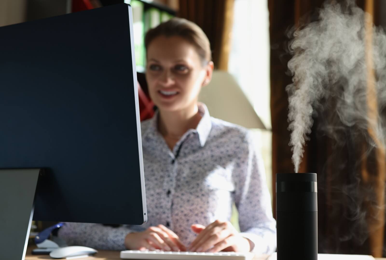 A woman working at her desk with a desktop humidifier to keep her workspace humidified and her eyes comfortable