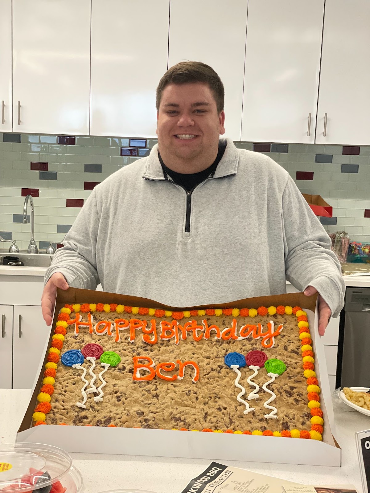 A SpotOn Employee posing and smiling with a birthday cookie cake.