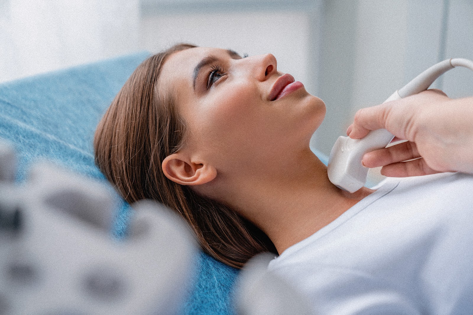 A female patient smiling while a doctor performs a thyroid ultrasound