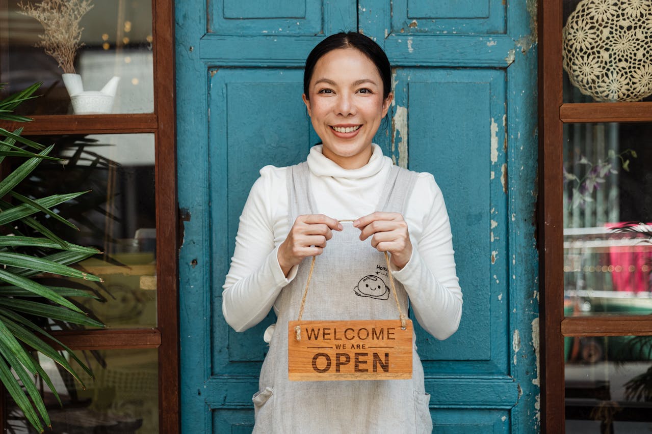 A woman holding a "Welcome Open" sign.