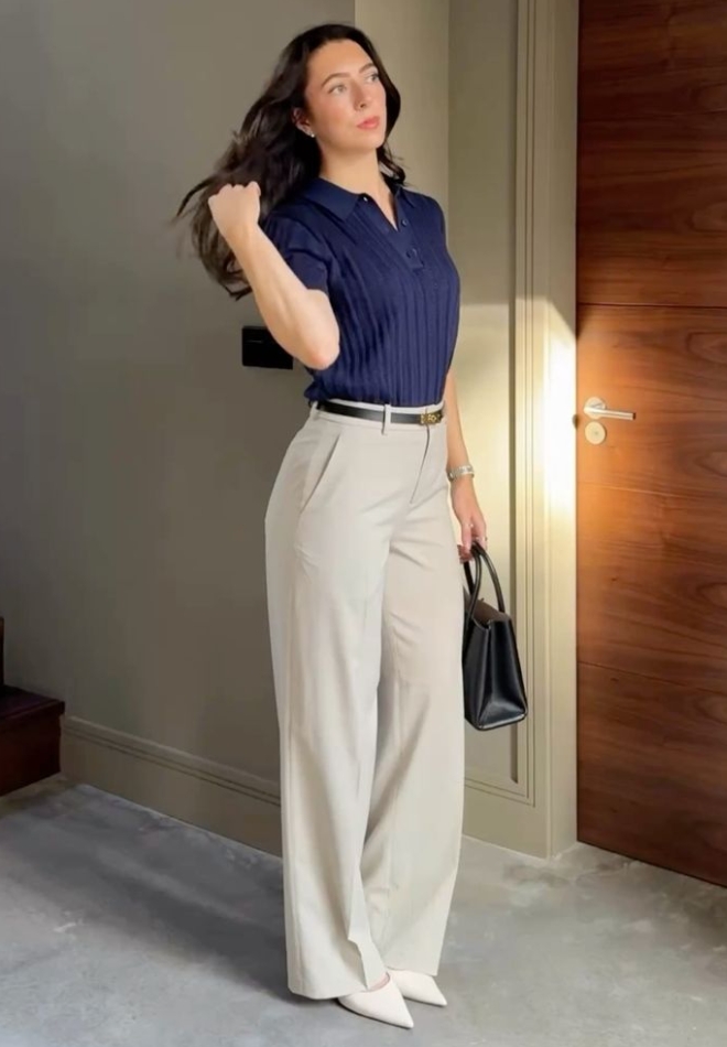 Wanita dengan trouser cream dan polo navy.
