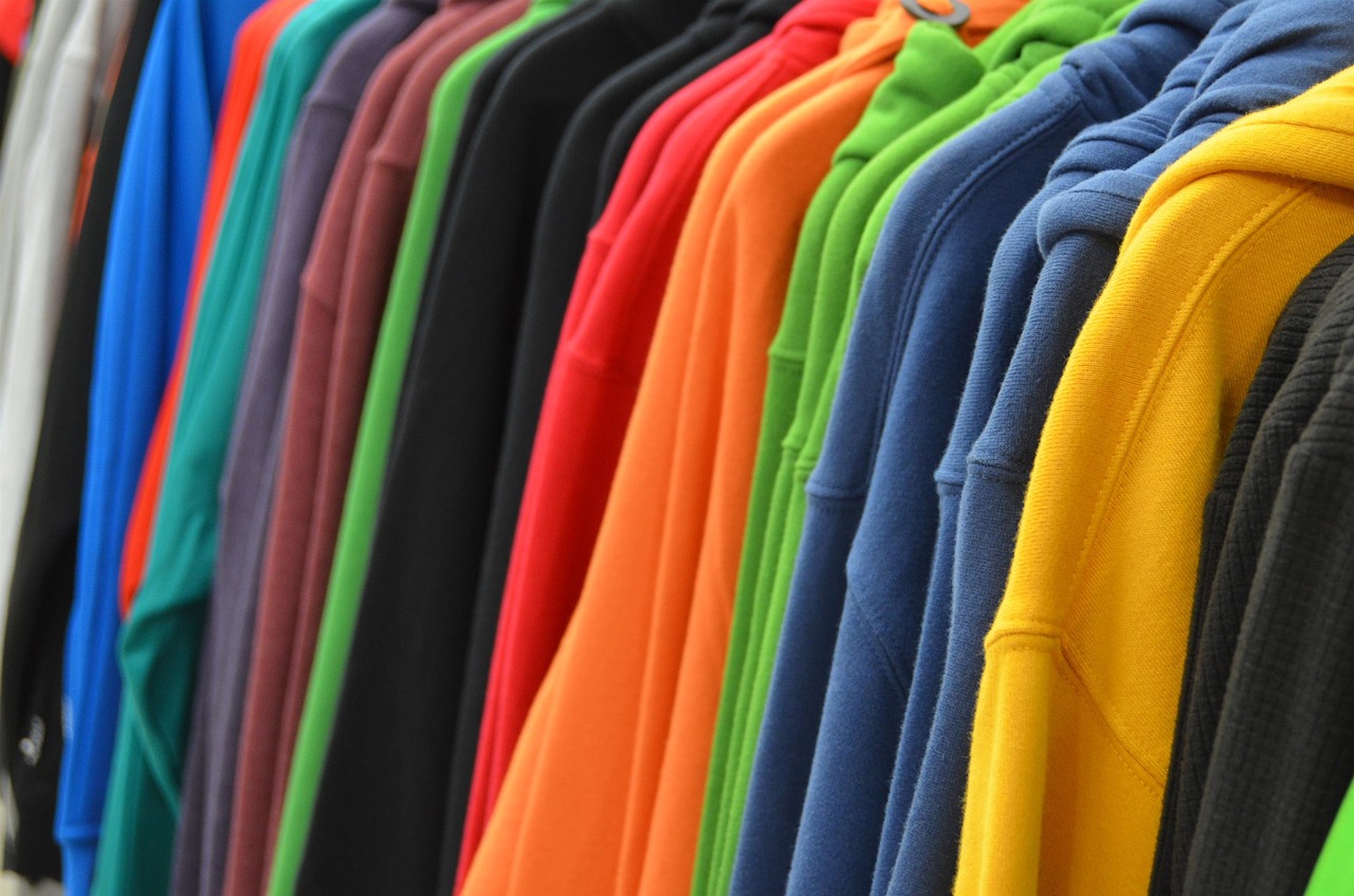 Brightly colored sweatshirts hanging on a rack. 