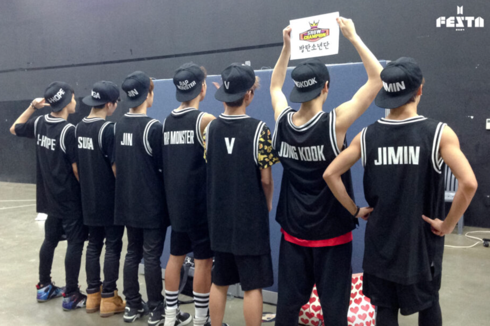 A piocture of BTS members with their names on the back of there shirt