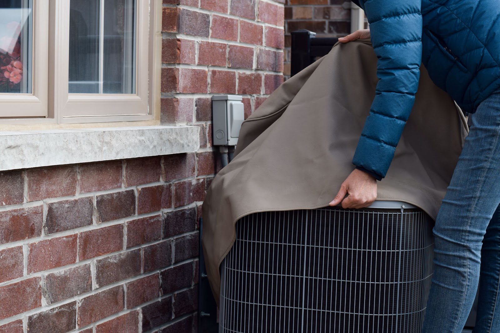 Person putting a cover over an AC unit. 