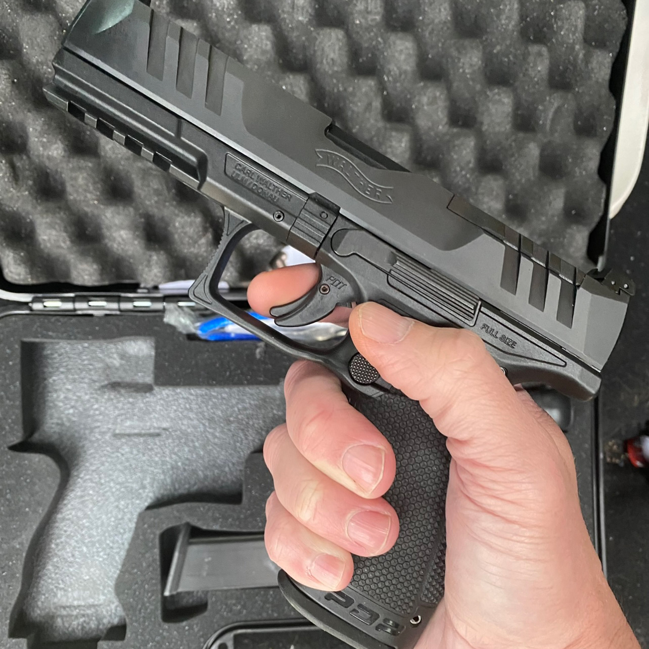 Walther PDP pistol in a man’s hand, pistol case in the background.