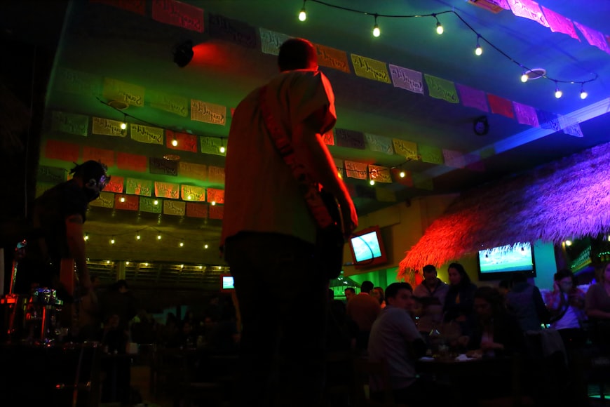  a man standing in front of a TV in a room filled with people