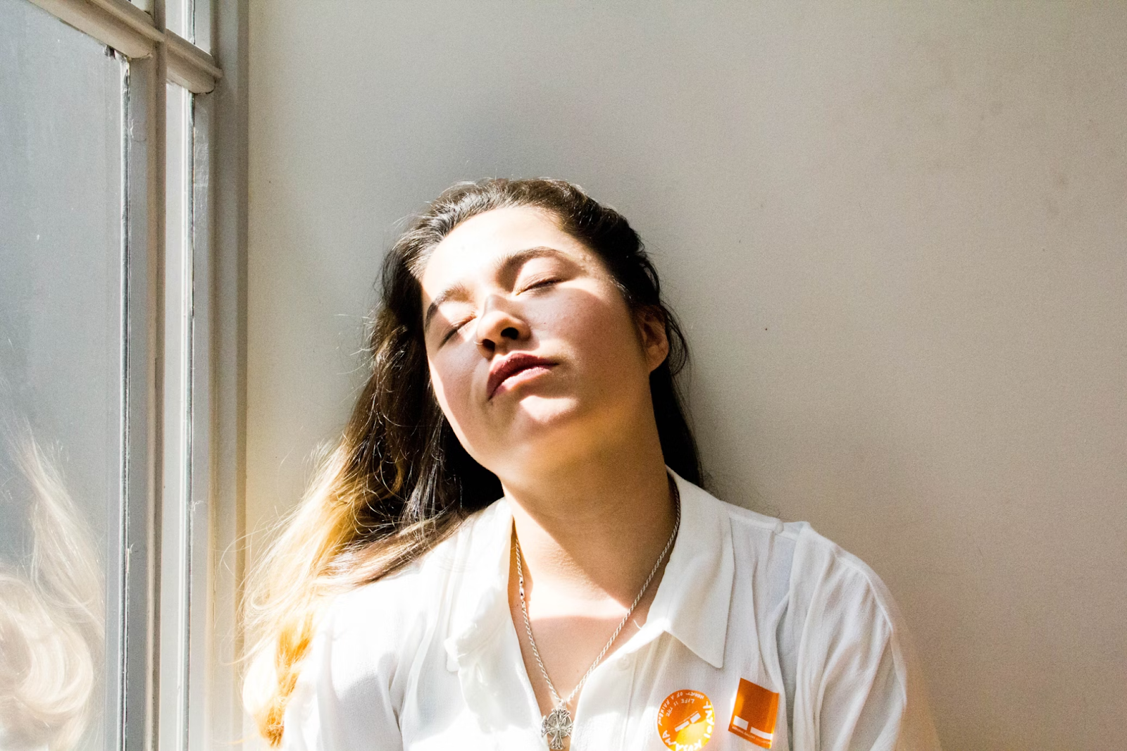 Woman standing near window with her eyes closed