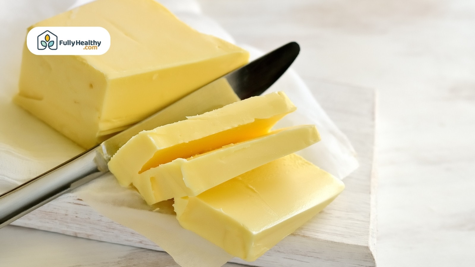 Sliced butter with knife on parchment paper surface