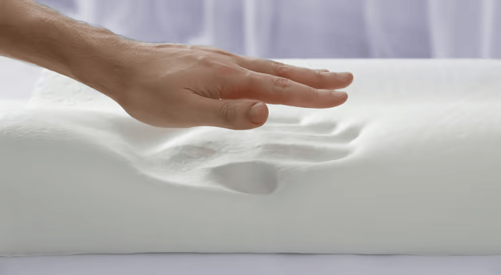  A hand pressing into a memory foam pillow, showcasing its conforming properties