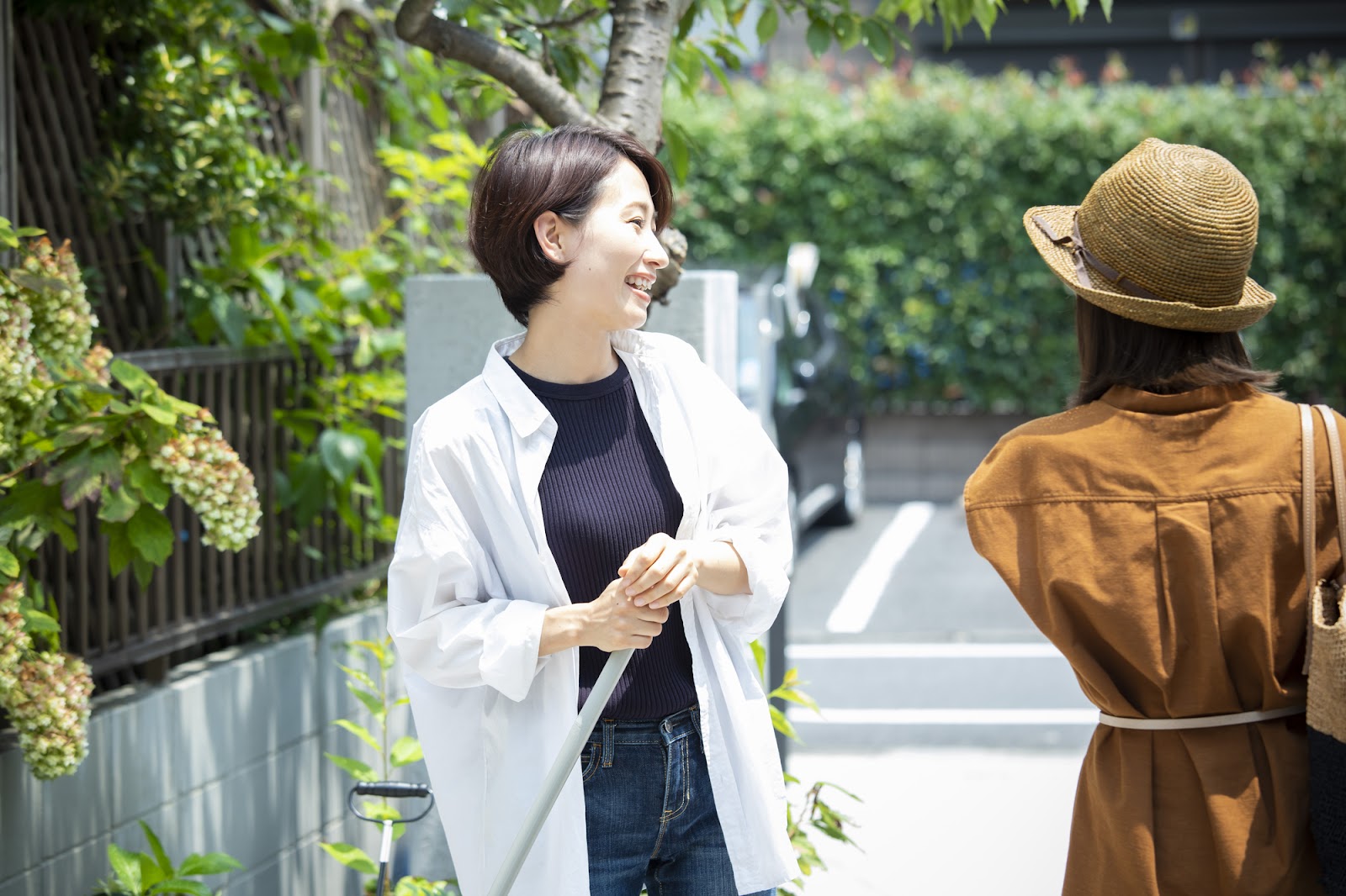住宅街であいさつを交わす女性たち。ご近所付き合いの良さがわかる地域の暮らしやすさを表現