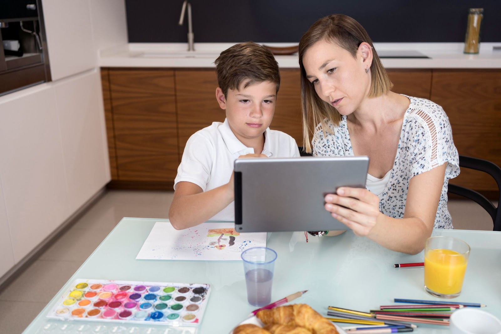 Adorable young boy checking tablet with mom.