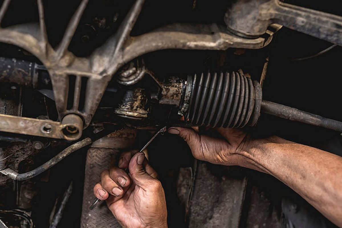 A mechanic is working on the steering rack to repair it for full functioning