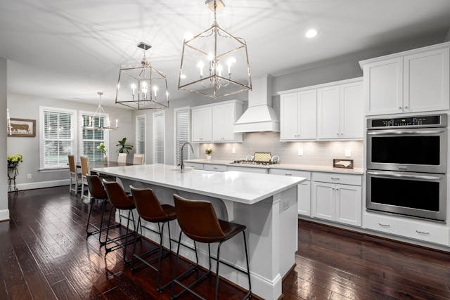 white kitchen with two chandeliers over the island 