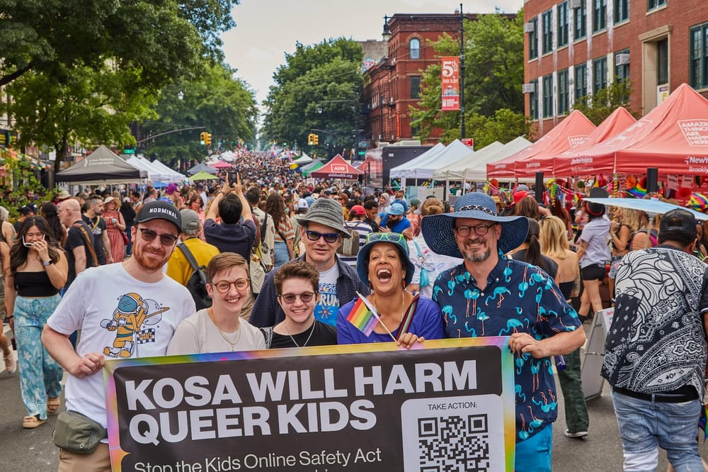 A group of advocates in front of a Pride event holds up a banner reading "KOSA will harm queer kids."