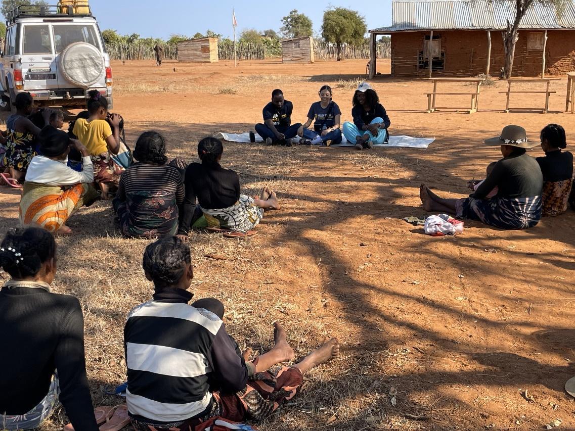 A group of people sitting on the ground

Description automatically generated