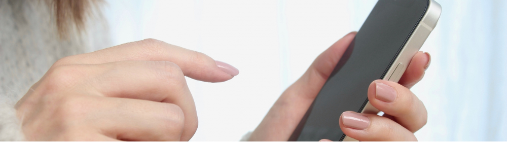 女性の手元をクローズアップし、指でタップしながらスマートフォンを操作している様子を捉えたイメージ