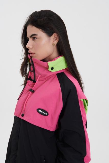 Mulher em pé de lado posando para foto com blusa verde e rosa