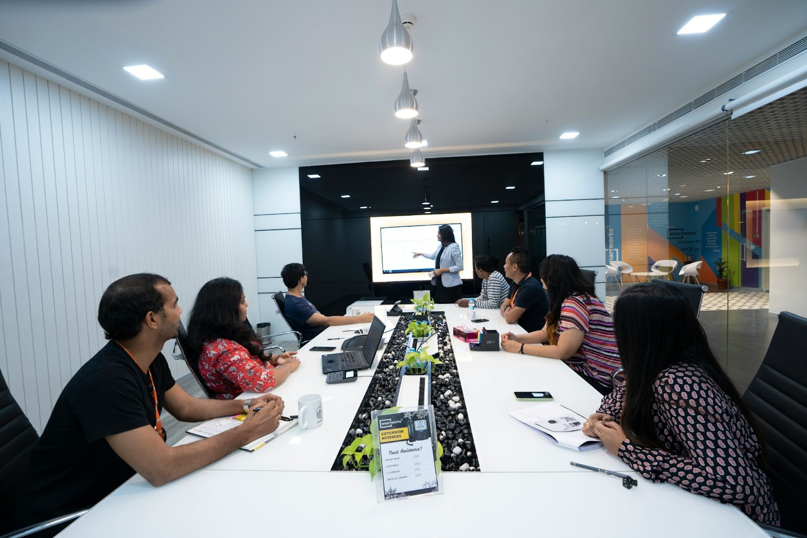 a team sat around a table using interactive whiteboard software to collaborate