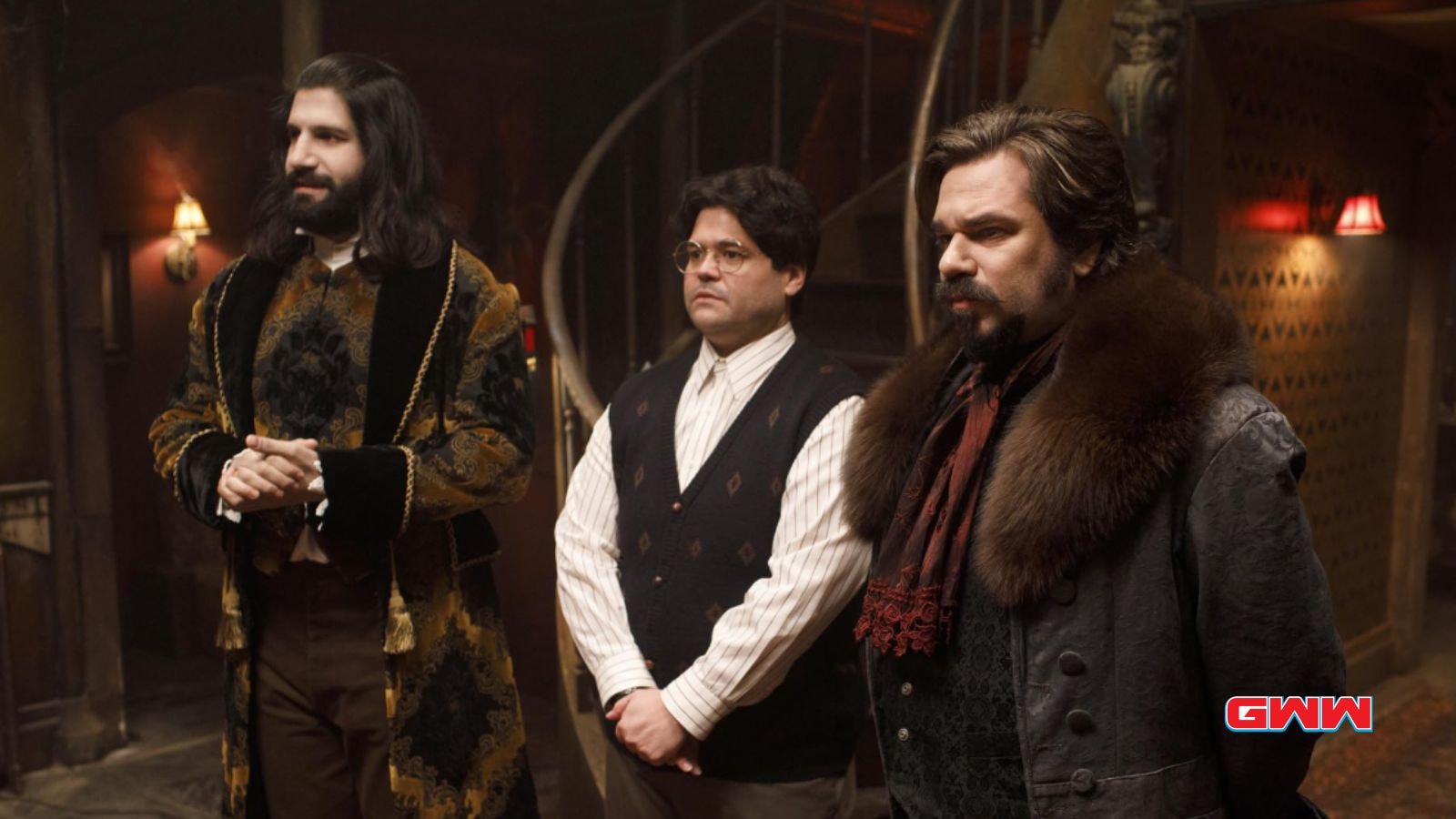 Lazlo, Guillermo, and Nandor  in historical attire standing together in a dimly lit room.