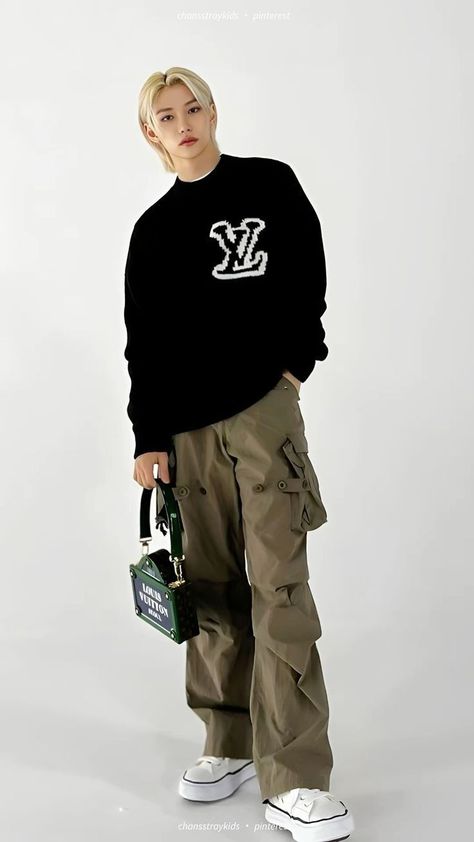 This contain Felix in black sweater and khaki cargo pants with white sneakers standing against a white background