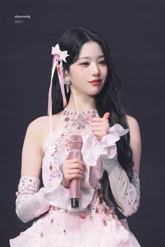 This contains an image of: Wonyoung' wearing a light pick gown with a microphone on her hand