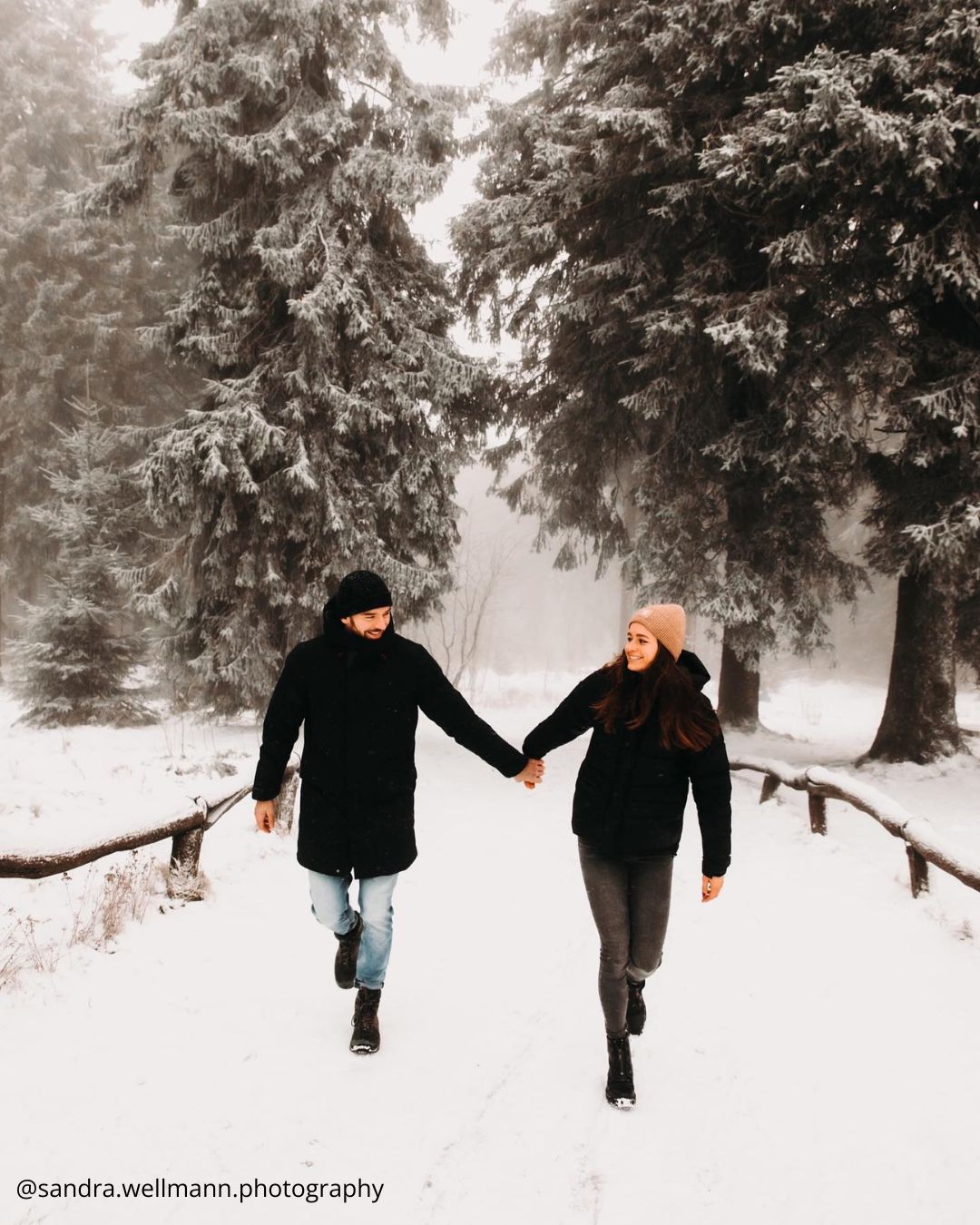 winter engagement photos a couple walking in the snowy forest