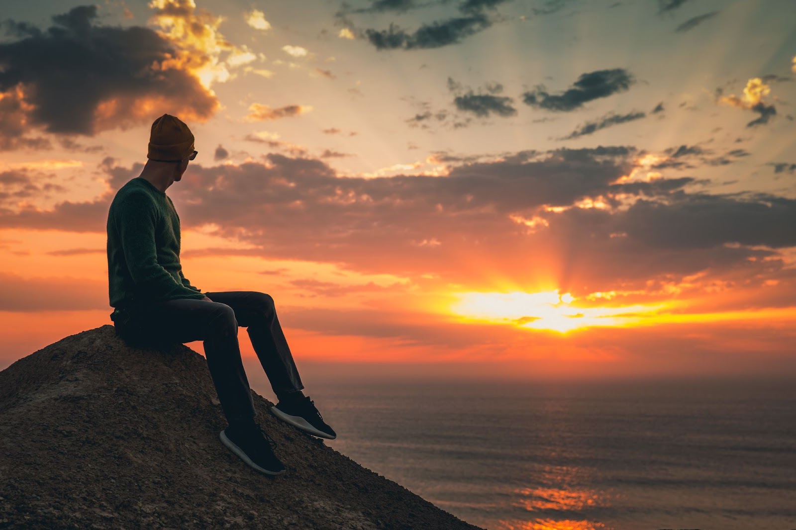 person sitting on a hill at sunset