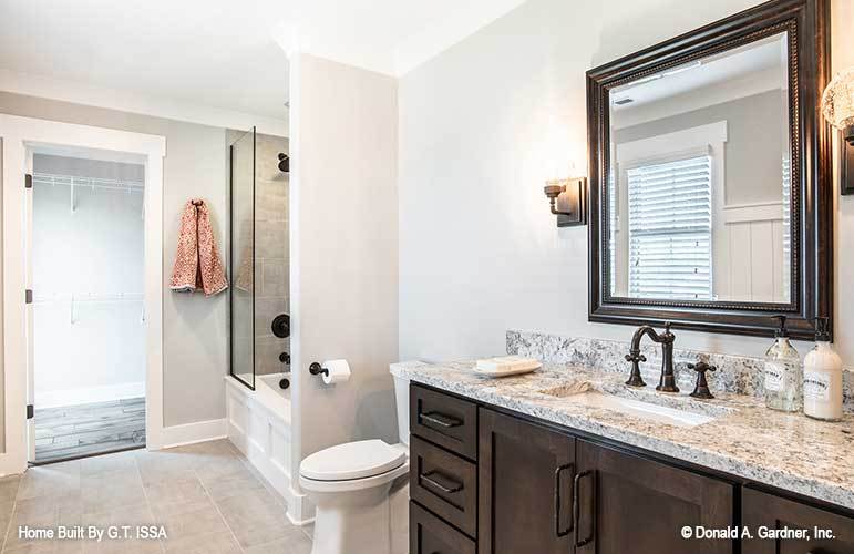 This bathroom is equipped with a sink vanity, a toilet, and a tub and shower combo enclosed in sliding glass door.