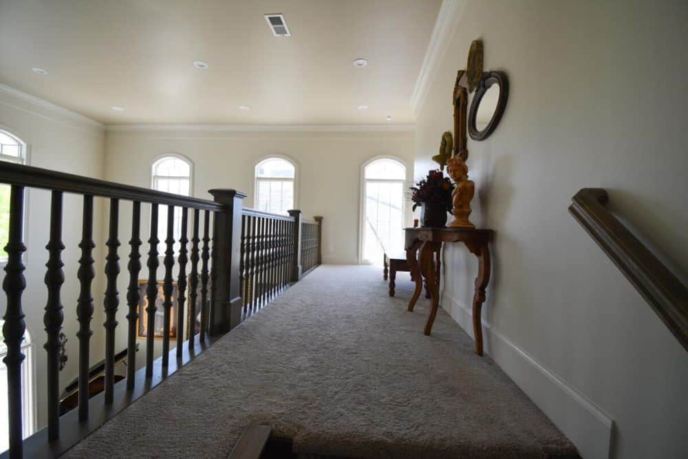 Balcony loft with a wooden console table graced with a bust sculpture, a flower vase, and wall mirrors.