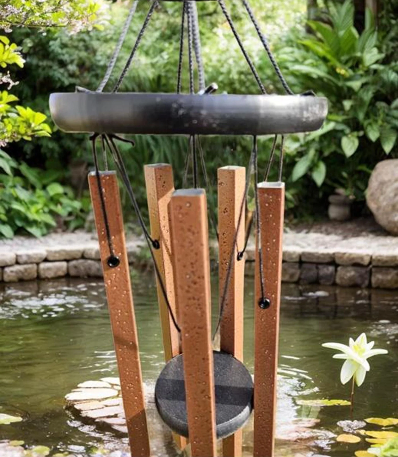 Unique windchimes with textured copper tubes and black circular top plate, featuring multiple harmonically-tuned tubes for deep resonant tones, photographed against natural garden backdrop