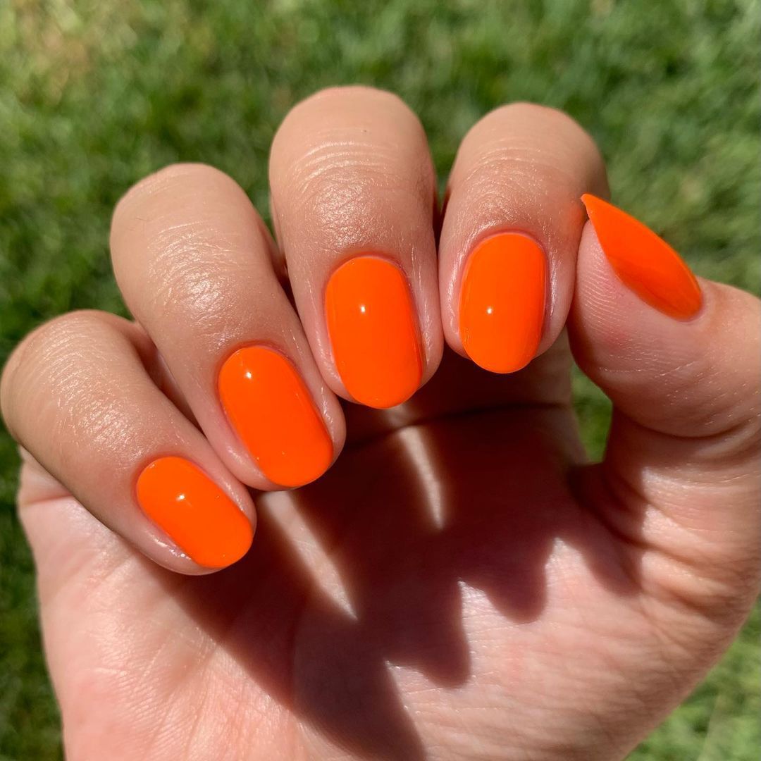 Close up of nails with glittery orange nails having Short Orange Nails