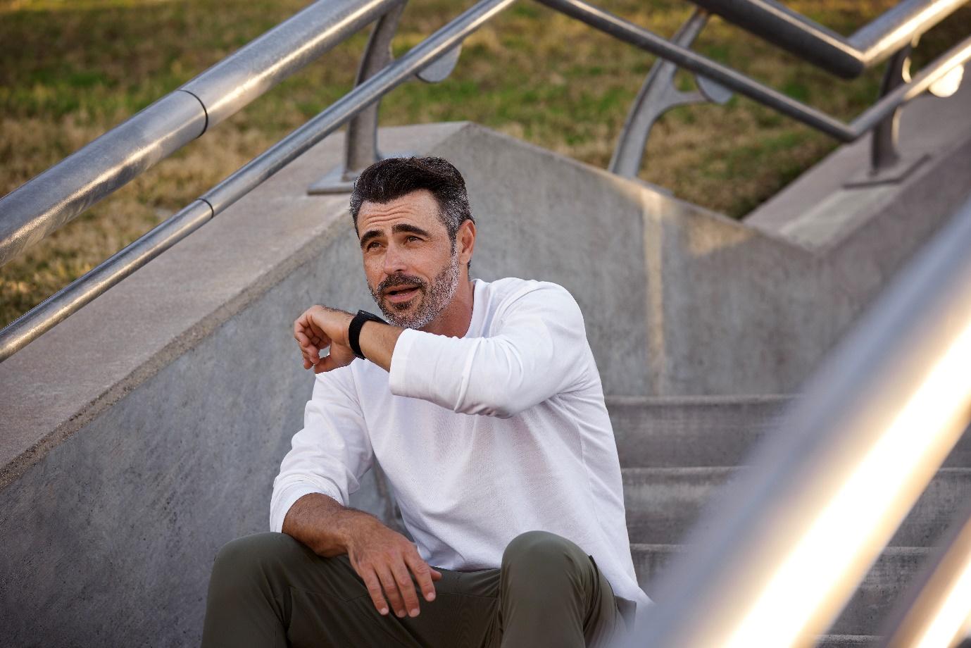 A person sitting on stairs looking at his watchAI-generated content may be incorrect.