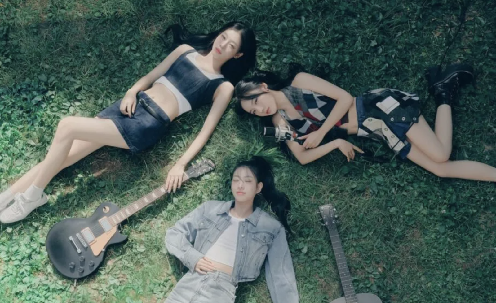 A picture of FIFTY FIFTY members Saena, Aran, and Sio lying on the ground 