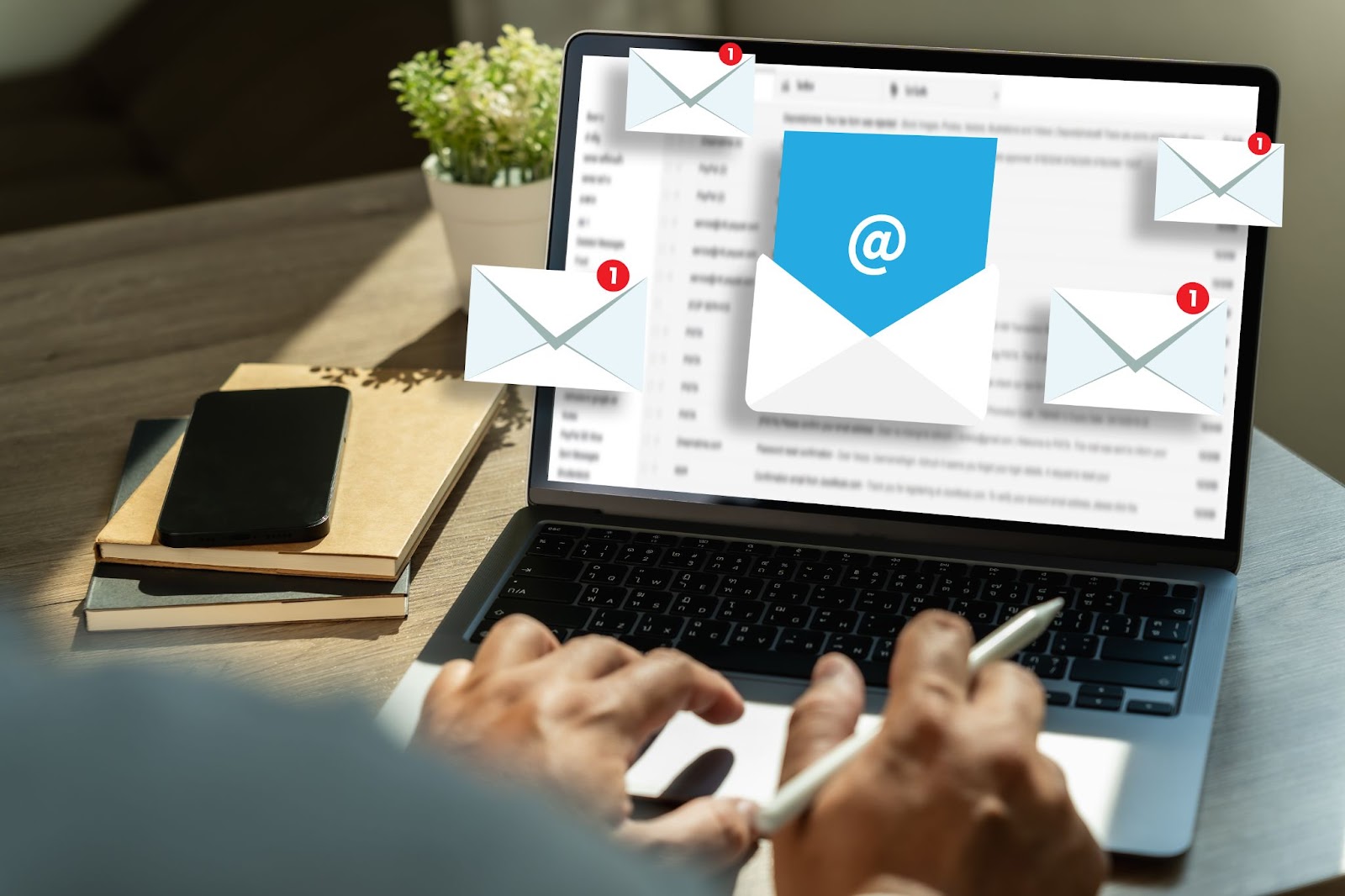 Email notifications on a laptop screen while a person types with a stylus.