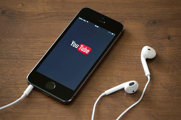 YouTube application on Apple iPhone 5S Kiev, Ukraine - June 5, 2014: Brand new Apple iPhone 5S with YouTube application service on the screen lying on a desk with headphones. YouTube is the world's most popular online video-sharing website that founded in February 14, 2005 youtube  stock pictures, royalty-free photos & images