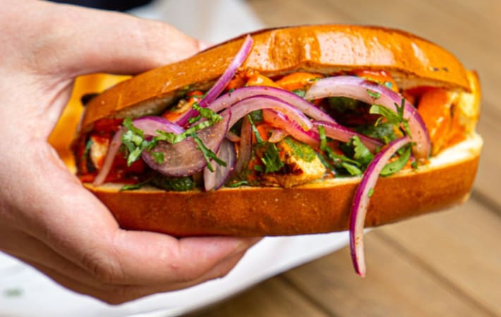 Hand holding a cheesy Paneer roll.