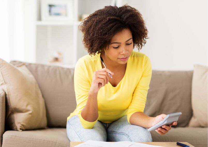 lady wearing a yellow long sleeve and holding a calculator and pen