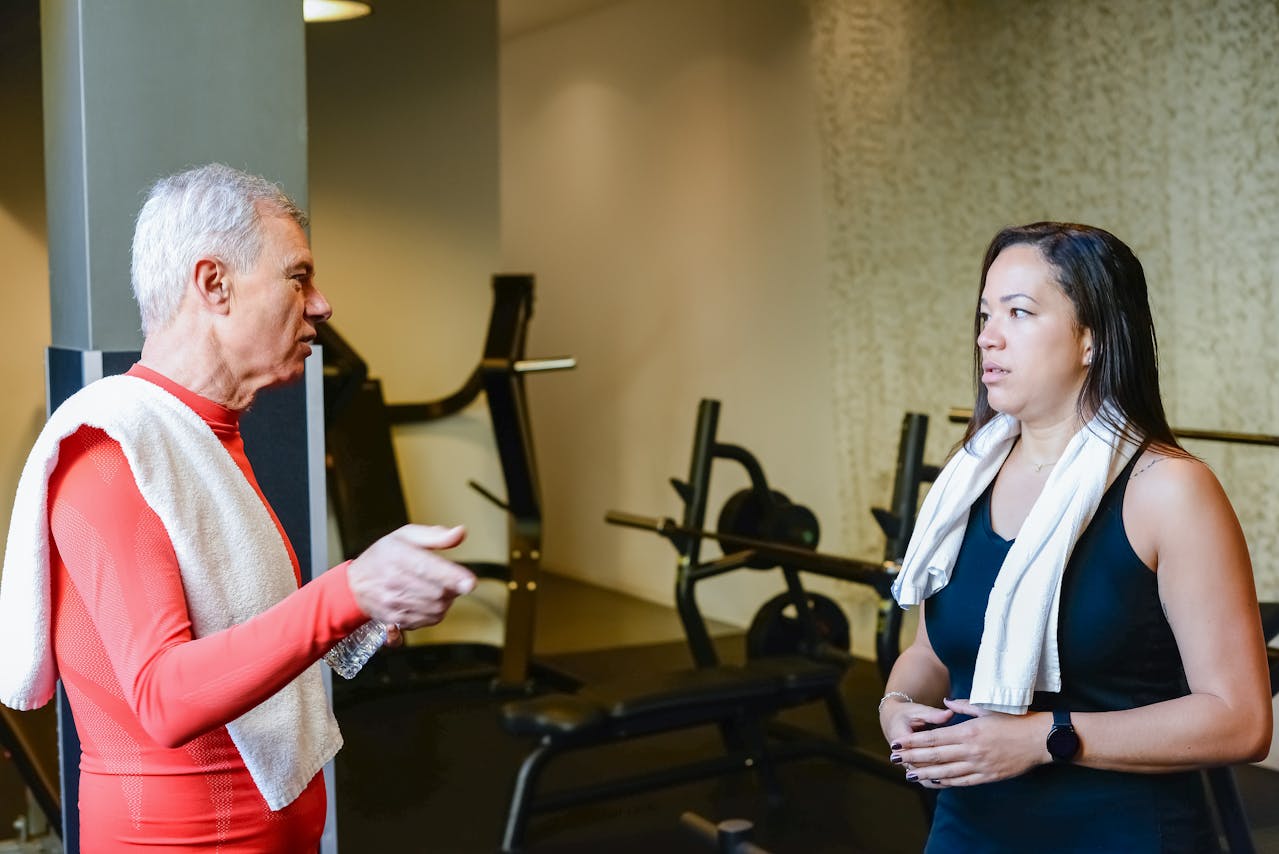 Two people having a focused discussion in a gym setting, highlighting efforts to improve team communication.