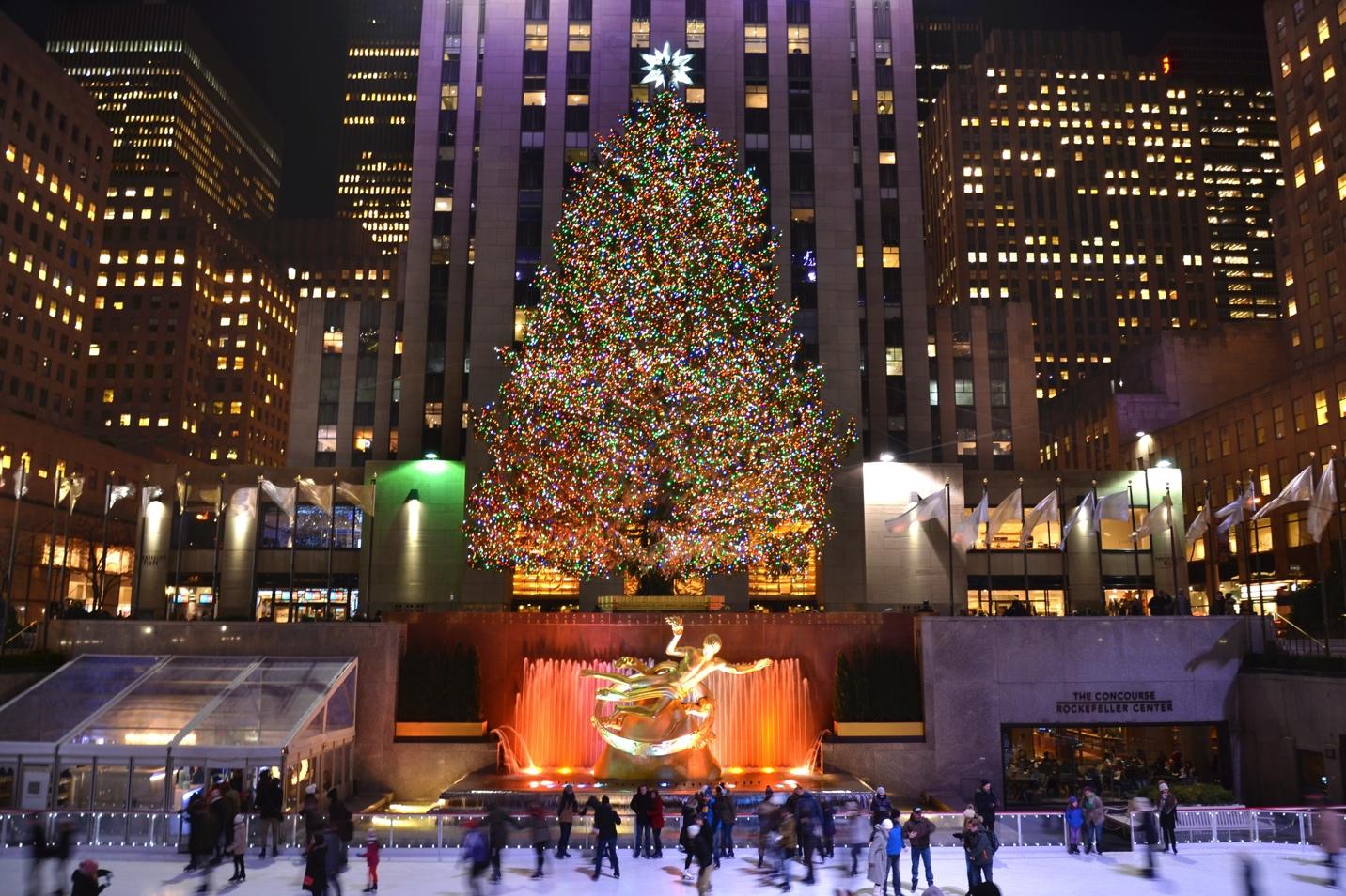 A large tree with lights and people skating on ice with Rockefeller Center in the background

Description automatically generated with medium confidence