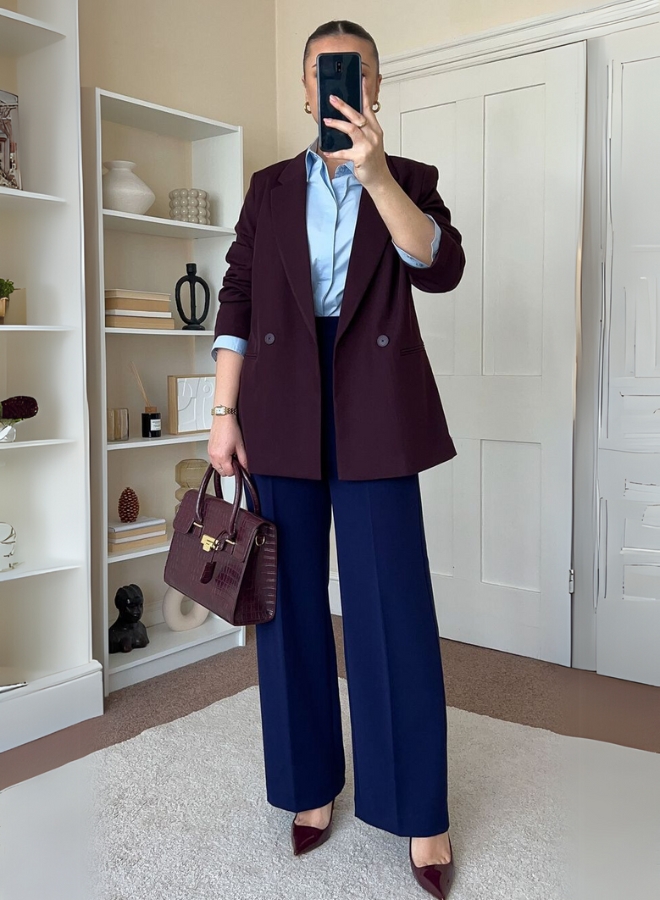 Wanita dengan baju biru dan blazer burgundy.