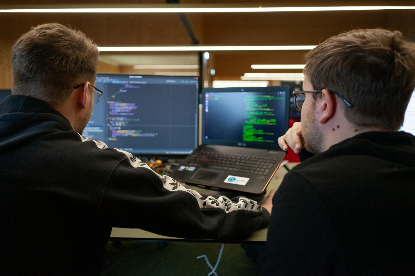 two men sitting in front of a laptop computer