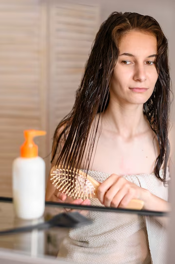 Woman brushing hair after washing it and applying serum